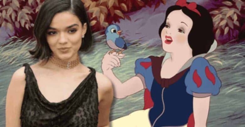 A person in a black dress poses next to an image of the animated character Snow White holding a bluebird. The background features a forest scene with foliage.
