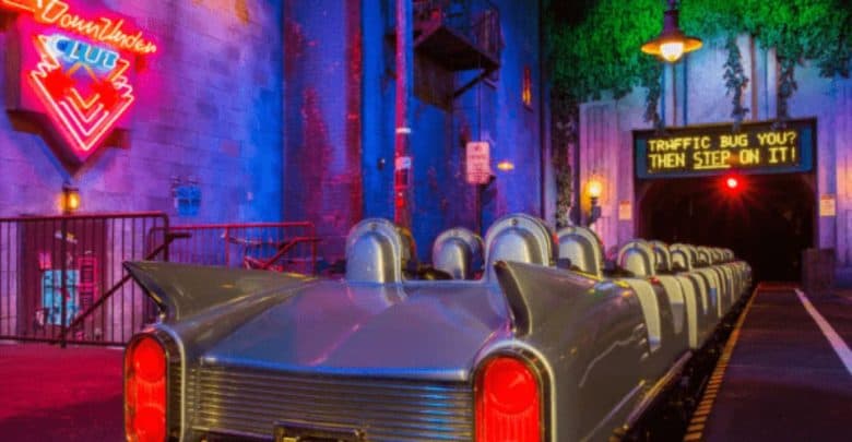 A retro car-themed amusement ride awaits in a neon-lit environment reminiscent of the Disney Rock 'n' Roller Coaster. The vehicle resembles a vintage convertible, facing a tunnel with a humorous sign that reads, "Traffic bug you? Then step on it!" Neon signs create a vibrant, nostalgic vibe.