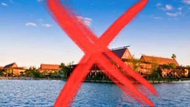 Lake view of the Magic Kingdom Polynesian Resort with large buildings at sunset, overlaid with a large red 'X' mark.