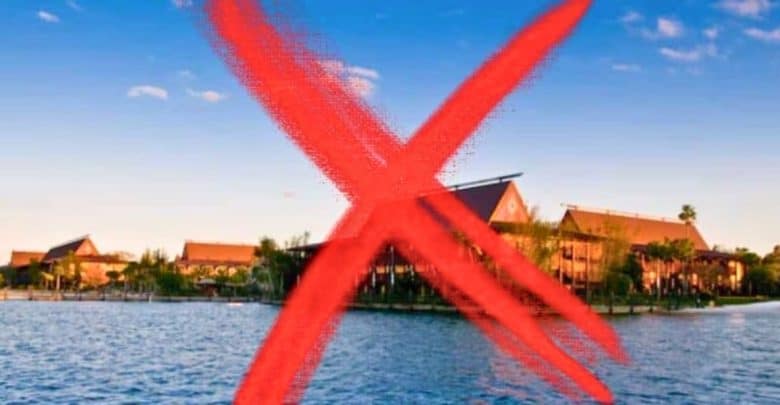 Lake view of the Magic Kingdom Polynesian Resort with large buildings at sunset, overlaid with a large red 'X' mark.
