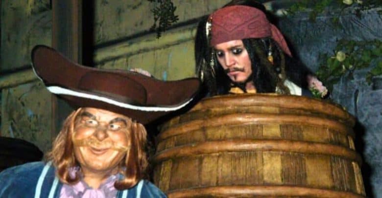 A wax figure of captain jack sparrow peering from behind a barrel next to a character with a wide-brimmed hat, resembling a scene from a pirate-themed setting.