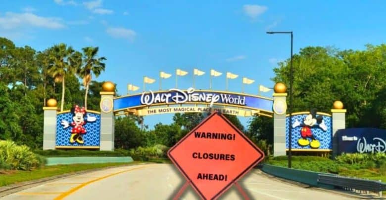 A road leading to the entrance of Walt Disney World, featuring colorful signs with Mickey and Minnie Mouse on either side. In the foreground, a bright orange warning sign reads "Warning! Closures Ahead!" against a backdrop of Disney-themed trees and a clear blue sky.