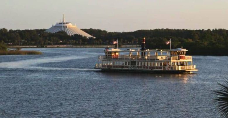 A boat sails across Seven Seas Lagoon with Space Mountain in the background