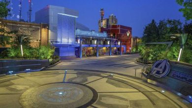 As dusk settles over Avengers Campus, the Stark Industries building and themed structures are beautifully framed by lush greenery. The Avengers logo stands out prominently on the ground, while nearby, Disneyland offers some of its best drinks for you to enjoy amidst this heroic setting.