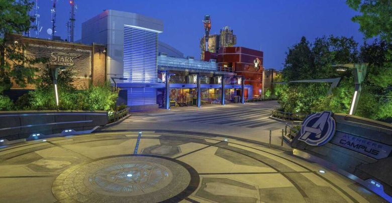 As dusk settles over Avengers Campus, the Stark Industries building and themed structures are beautifully framed by lush greenery. The Avengers logo stands out prominently on the ground, while nearby, Disneyland offers some of its best drinks for you to enjoy amidst this heroic setting.