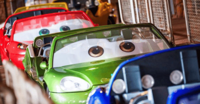 Colorful cartoon-themed cars line up on a track at Disneyland, each with large expressive eyes on the windshields. These vibrant vehicles resemble animated characters, featuring lively hues like green, red, and blue.