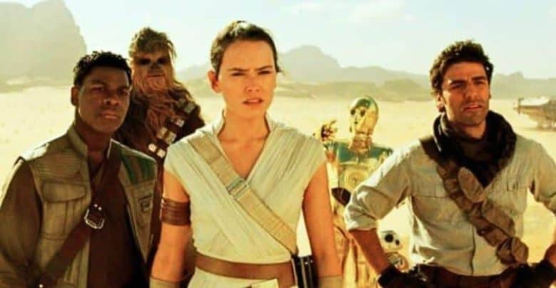 A group of characters stands in a desert landscape under a bright sky. They look determined, with some wearing rugged clothing and others in costumes with futuristic elements. A spacecraft and droid are visible in the background.