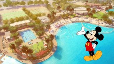 Illustration of Mickey Mouse standing beside an aerial view of a resort with pools, lounge chairs, palm trees, sports courts, and landscaped grounds under a sunny sky.