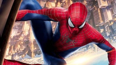 Spider-Man in his red and blue suit clings to the side of a building, with the city skyline in the background, appearing upside down.