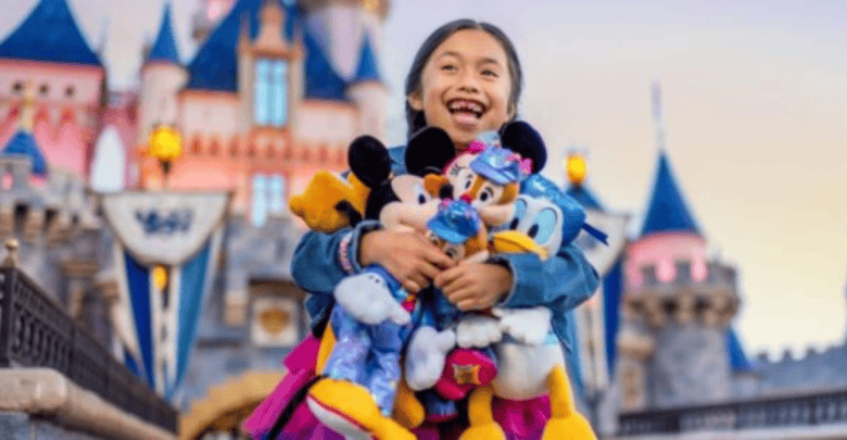 A joyful child holds multiple plush Disney characters, including Mickey, Minnie, and Donald, in front of a colorful fairy-tale castle at a theme park. The background features spires and flags, suggesting a magical atmosphere within Disney World and Disneyland.