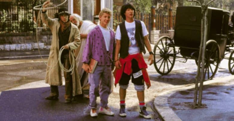 Three young men dressed in colorful, casual 1980s attire stand on a street next to an older man in Western-style clothing holding a lasso. A vintage horse-drawn carriage is in the background, partially visible near a tree.