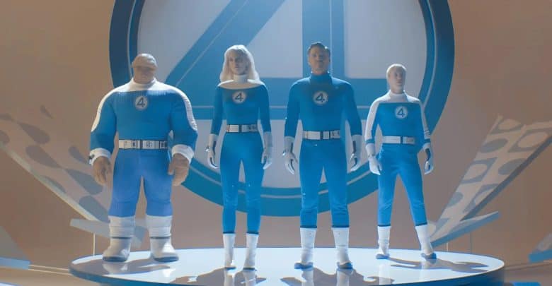 Four people wearing blue and white superhero costumes with the number "4" on their chests stand on a circular platform in front of a large "4" symbol, capturing the excitement as Kevin Feige talks about Fantastic 4. The scene features a bright, futuristic design.