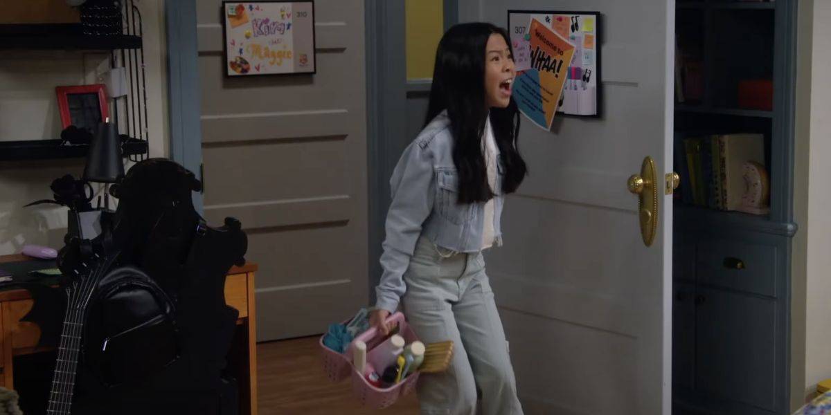 A young woman with long black hair, wearing a light denim jacket and jeans, stands in a doorway holding a pink basket of art supplies, appearing surprised or upset in a room decorated with colorful posters.