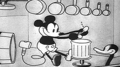 Black-and-white cartoon image of Mickey Mouse using a spoon to hit a metal trash can, surrounded by hanging pots and pans, with Donald Duck's head peeking in from the side.