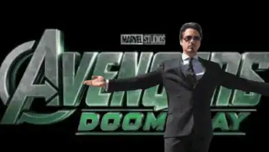 A man in a suit stands with arms wide open in front of a large "Avengers: Doomsday" logo with the Marvel Studios label above it, set against a plain black background.