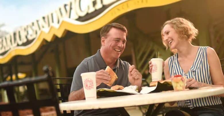 A man and woman sat eating outside Earl of Sandwich in Disney Springs