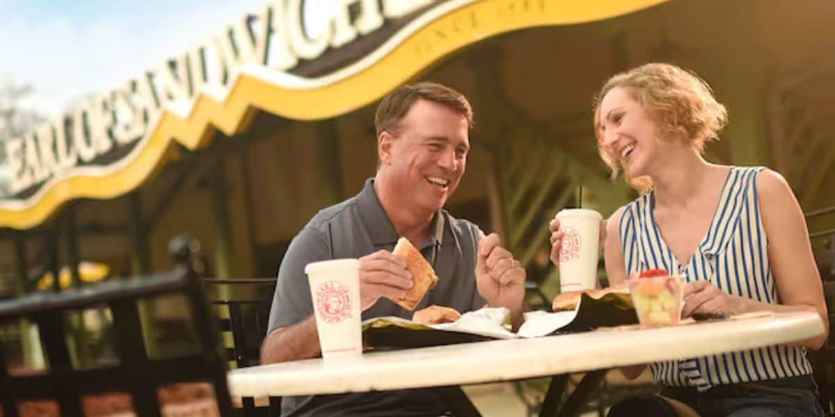 A man and woman sat eating outside Earl of Sandwich in Disney Springs