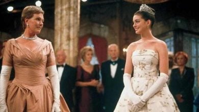 Princesses in sparkling gowns greet each other at a royal Disney ball, with guests in elegant attire mingling around them.
