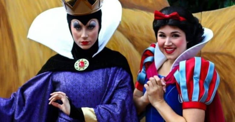 The Evil Queen and Snow White greeting guests in vibrant costumes at a Disney park, ready for photos and magical encounters.