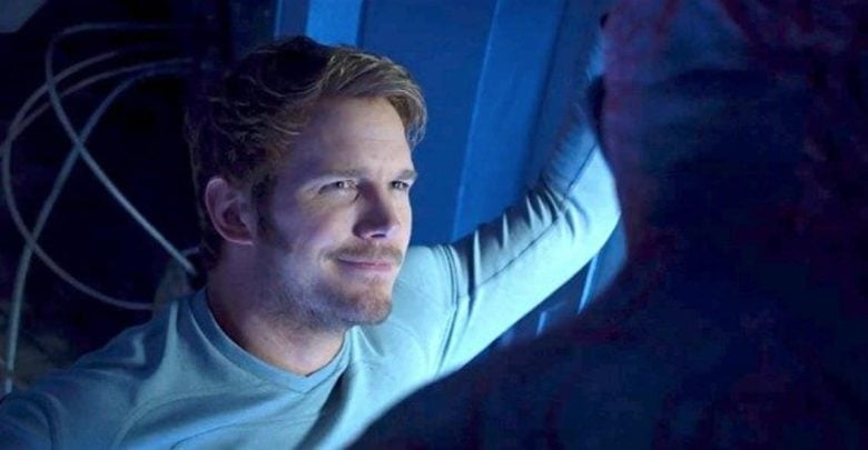 A guest in a Captain America tee grins by a blue Marvel wall, chatting about Avengers plots with another fan in dramatic lighting.
