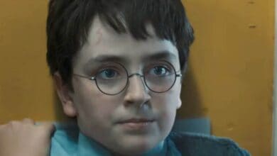 Harry Potter, in signature glasses and dark hair, sits calmly by a yellow wall—evoking the magic of HBO’s new Wizarding World.