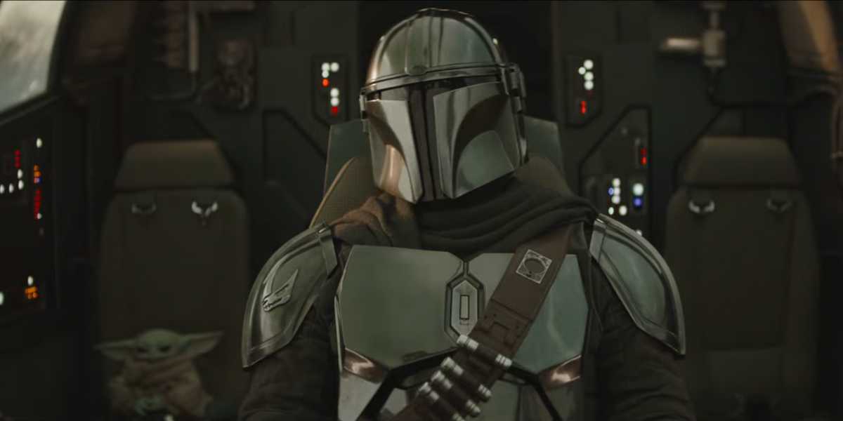 The Mandalorian and Grogu experience a thrilling adventure in the Star Wars: Galaxy’s Edge cockpit, surrounded by iconic controls.
