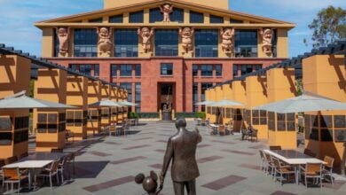 The Partners statue of Walt Disney and Mickey Mouse stands before the Seven Dwarfs building with outdoor seating at Disneyland.
