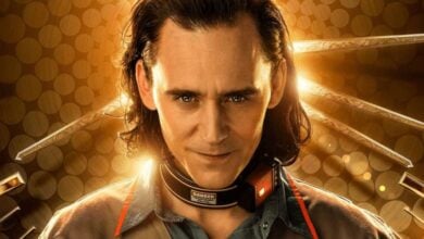 Loki, with his signature long hair and collar, stands before a glowing clock backdrop, giving a sly smile at Avengers Campus.