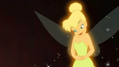 Tinker Bell glows amid sparkling lights, her green dress and wings shining against a magical nighttime backdrop.