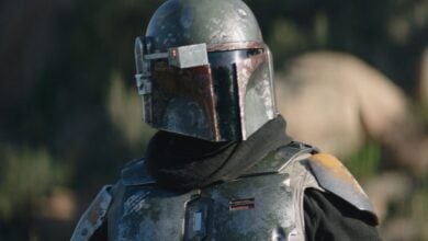 The Mandalorian, clad in weathered armor and helmet, greets fans amid the immersive Star Wars setting at the theme park.