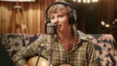 A performer with headphones rocks out on guitar and sings into a mic, creating pop-star magic in a studio setting.
