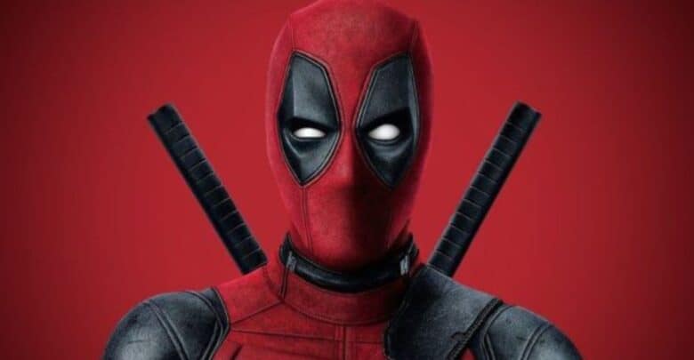 Deadpool, played by Ryan Reynolds, strikes a pose in his unmistakable red and black suit with twin swords strapped to his back, standing against a dramatic red backdrop. Marvel fans at the theme park are buzzing with excitement for his upcoming Avengers: Doomsday appearance.