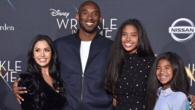 A cheerful family of four gathers for a photo on the red carpet at a Disney premiere, surrounded by festive movie-themed decorations and excited fans.