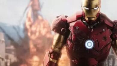 Iron Man, brought to life by Robert Downey Jr., stands heroically in his signature red armor, surrounded by swirling smoke and bursts of special effects on a thrilling Avengers Campus attraction stage.