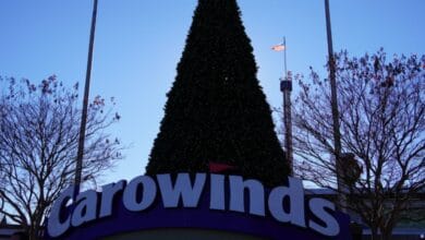 A large Christmas tree stands behind the Carowinds entrance sign during the park’s attraction closures.