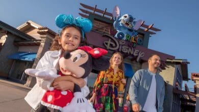 A child holding a Minnie Mouse plush in front of the World of Disney at Disney Springs.
