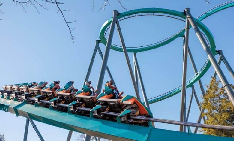Riders ascending a curved track loop on a Six Flags roller coaster.