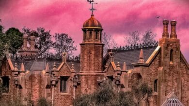 The Haunted Mansion at Magic Kingdom set against a vibrant pink sky.