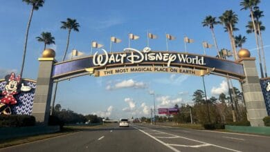Walt Disney World entrance archway featuring Mickey and Minnie Mouse icons illuminated by flashing lights.