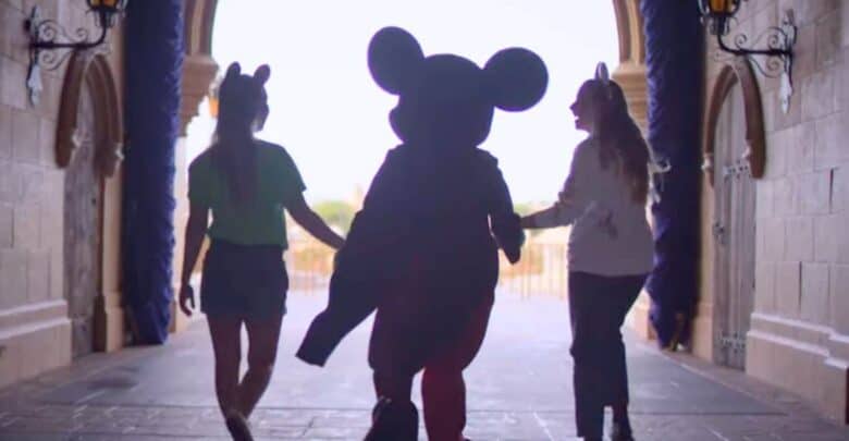 Mickey Mouse walks through the Cinderella Castle archway at Disney World holding hands with two guests involved in recent incidents.
