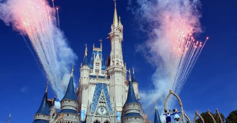 Fireworks light up Cinderella Castle at Disney World with Mickey and Minnie Mouse in the foreground.