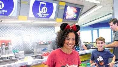 A guest wearing Minnie ears at Cosmic Ray’s Starlight Cafe in Magic Kingdom, featuring food policy information.