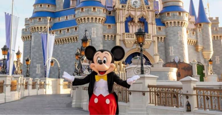 Mickey Mouse posing in front of Cinderella Castle at Disney World for Disney announcements.