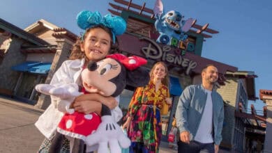 A child holds a Minnie Mouse plush in front of World of Disney at Disney Springs.