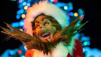 The Grinch in a Santa hat during Universal holiday travel.