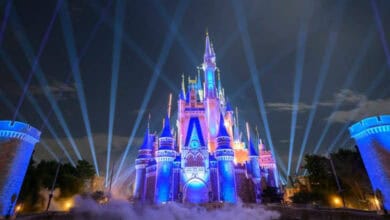 Cinderella Castle glowing in blue spotlights at night at Magic Kingdom, Walt Disney World.