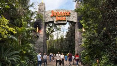 Guests pass through the Jurassic Park gates at Universal Studios, which are currently closed for River Adventure.