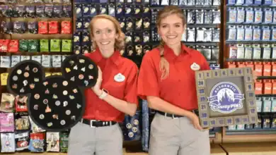 Two Disney World cast members hold a Mickey-shaped board and an advent-style display for Disney mystery pins.