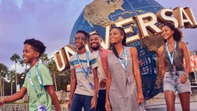 A family smiles in front of the Universal Studios globe, contrasting with theme park history at Disney World.