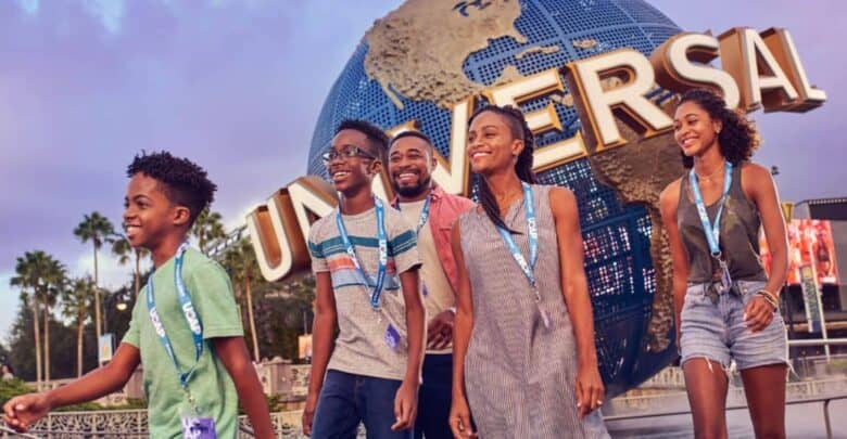 A family smiles in front of the Universal Studios globe, contrasting with theme park history at Disney World.